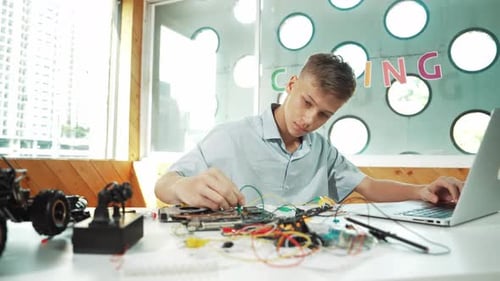 Teen Boy Working on Computer and Electronics Project