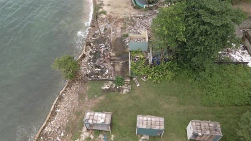 aerial birds eye view dolly shot of a abandoned derelict destroyed bungalow beach resort on the ocea