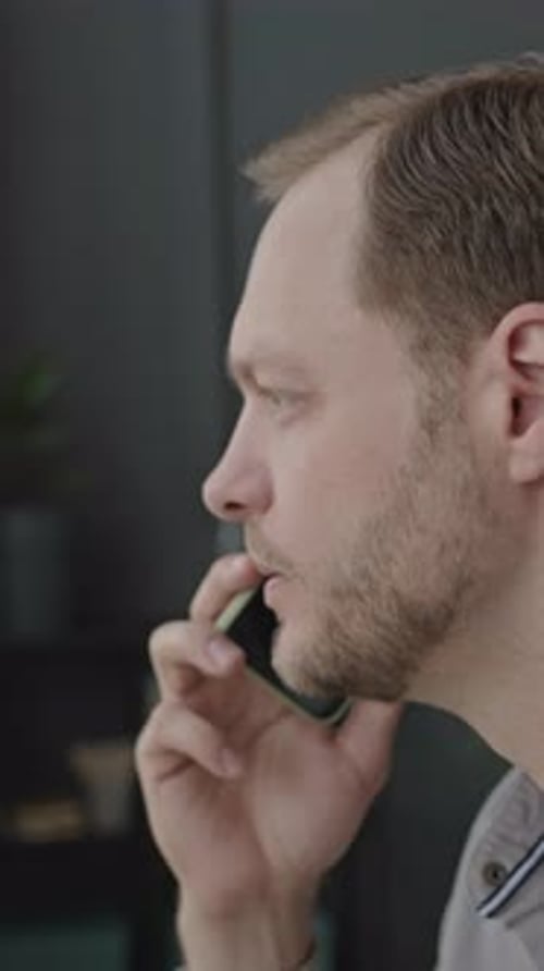Young Man Having Conversation on Mobile Phone in Office