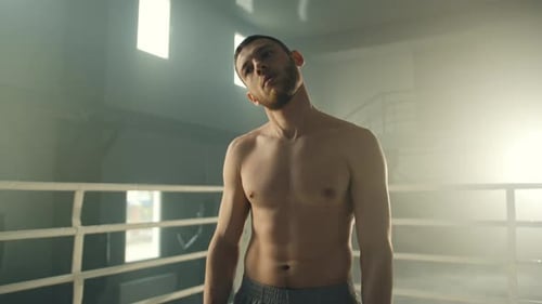 Shirtless Boxer Warming Up in a Gym Ring