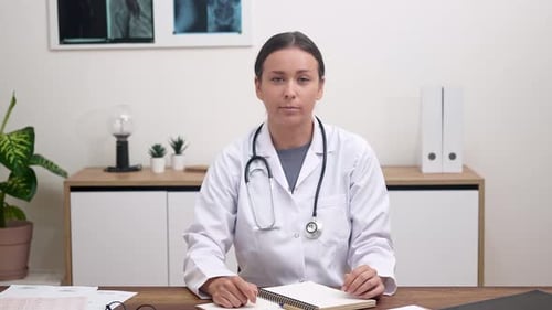 Woman Doctor Talking at Desk in Office