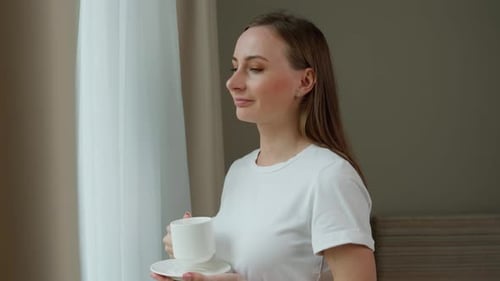 Woman Drinking Coffee by Window in Apartment