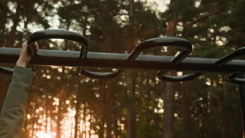 Close-up of Unrecognizable Woman Crossing Monkey Bars in Forest