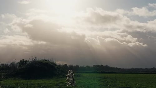 Sun Rays Breaking Through Clouds Over Countryside Field