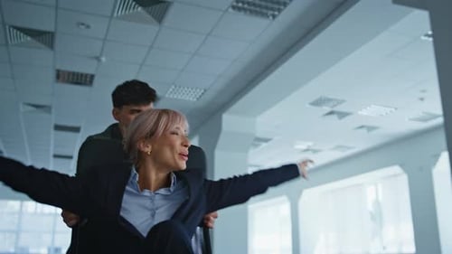 Carefree Coworkers Riding Chairs in Empty Space Closeup Colleagues Having Fun