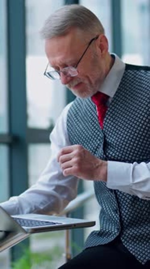 Mature Man Works on Laptop in Modern Office