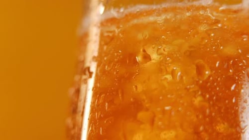 Closeup Wet Lager Glass with Golden Refreshing Beer Pouring Inside with Bubbles Tasty Cold Beverage
