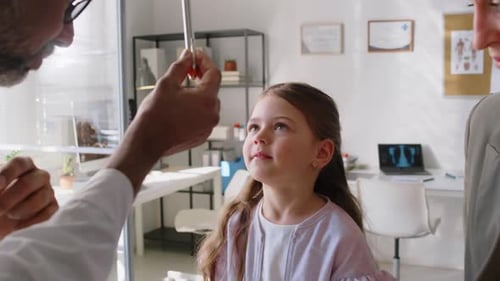 Asian Male Pediatrician Checking Little Girls Eye Reflexes during Checkup