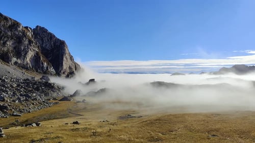 Beautiful landscape scene on the mountain in clouds and fog passing during a sunny day.