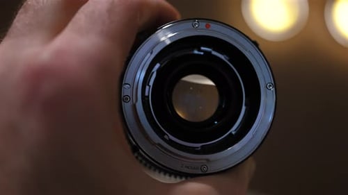 Close up of professional camera lens with aperture and focus rings being adjusted by hand