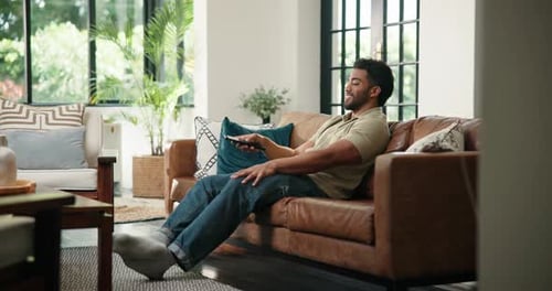 Relaxed Man Changing Channels on Living Room Couch