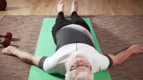 Senior Man Relaxing on Yoga Mat at Home