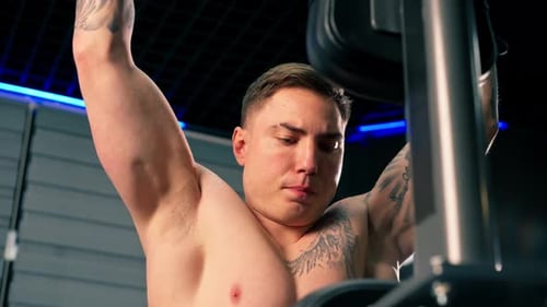 Close Up in the Gym Young Handsome Guy with Tattoos is Doing Pullups on the Horizontal Bar Shaking