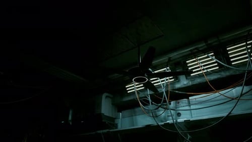 Spinning Ceiling Fan in Dark Industrial Tech Environment