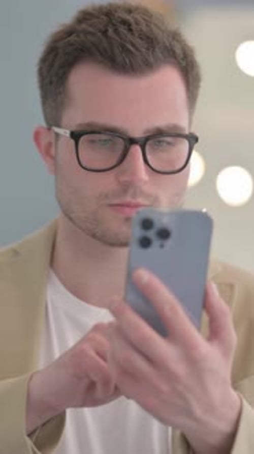 Man Celebrates Good News on Smartphone, Indoors