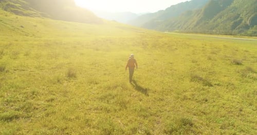 Flight Over Backpack Hiking Tourist Walking Across Green Mountain Field Huge Rural Valley at Summer