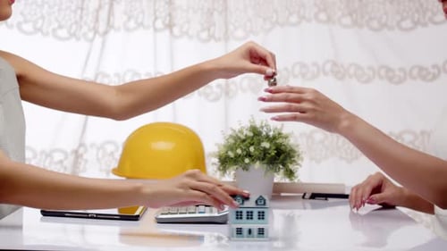 Eine Architektin oder Bauträgerin und ihr Kunde geben sich die Hand über ein Hausbau- und Kaufangebot