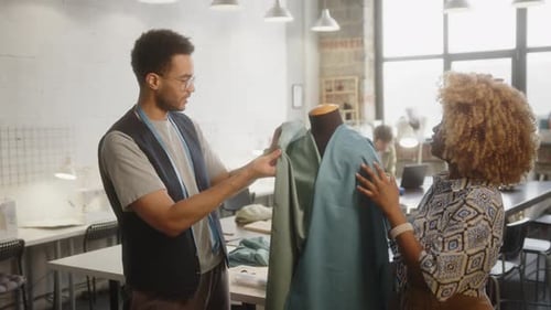 Schneiderinnen heften in der Nähwerkstatt Stoff an das Mannequin