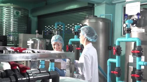 Technologist in bottling factory checking water bottles before shipment.
