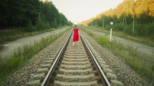 Rear View of Woman Running Along Railway Track Through Countryside