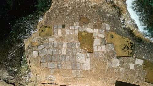 Ascending bird's eye aerial views of the salt pans of Xwejni on Gozo, Malta progressively zooming ou