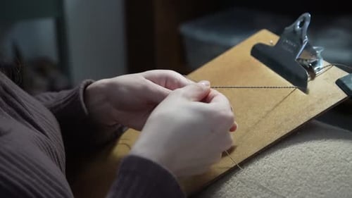 Person Creating Macrame Jewelry Design with String