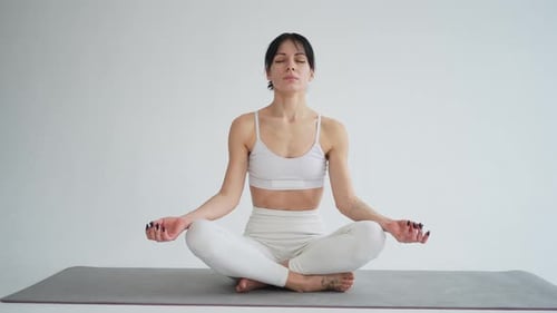 Woman Meditating Calmly on Yoga Mat Indoors