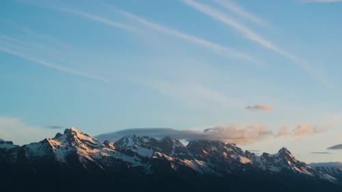 Timelapse of snow covered mountains at sunrise with clouds