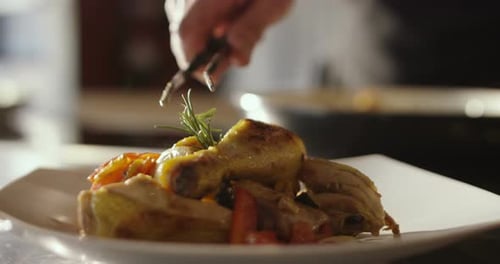 Super slow motion macro of roasted chicken legs with rosemary and grilled vegetables served on a w