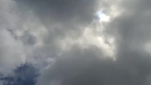 Zeitraffer bewegter dunkler Wolken über der am Himmel scheinenden Sonne.