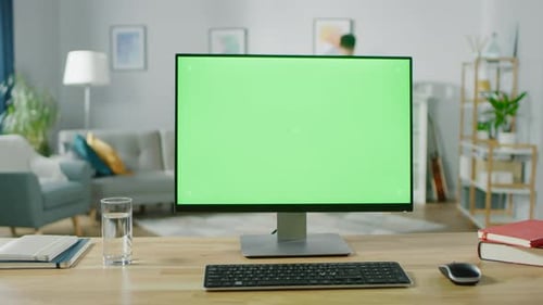 Modern Personal Computer with Green Mock-up Screen Display Standing on the Desk. In the Cozy and Li
