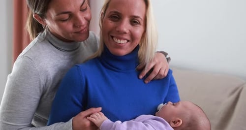 Female gay couple having fun with their baby son at home - Family, lgbt and love concept