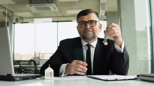Professional Man Holds Keys at Office Desk