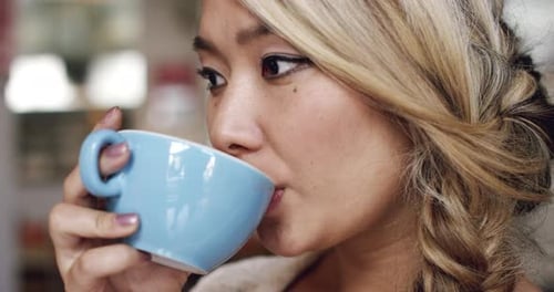 4k video footage of a beautiful young woman having a cup of coffee at the cafe