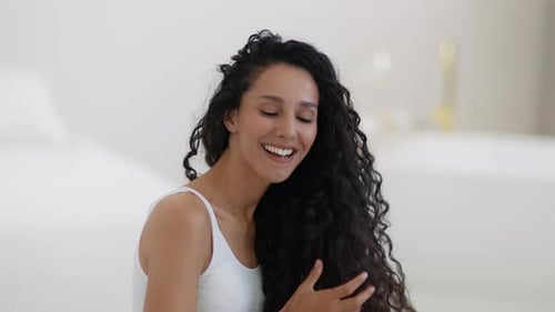 Smiling Woman with Curly Hair Posing Indoors