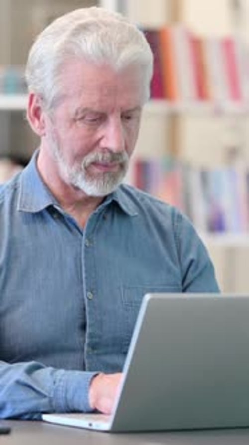 Senior Man Uses Laptop in Home Office Setting
