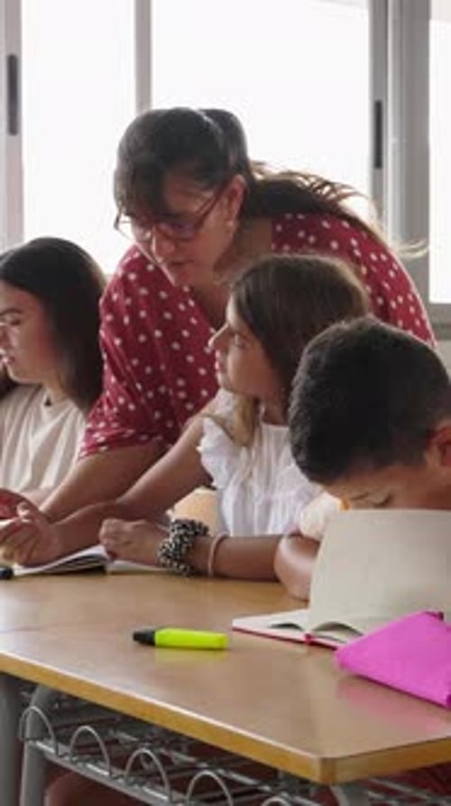 Female Teacher Assisting Elementary Student During Lesson at School
