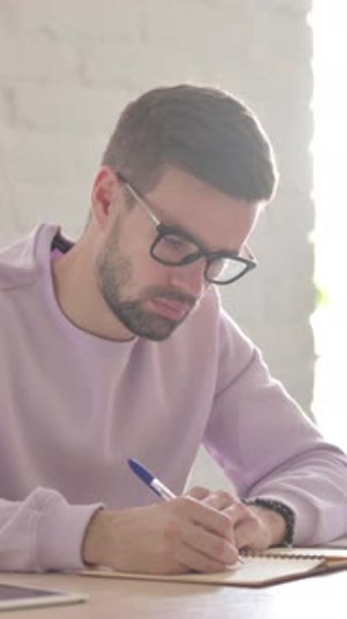 Young Man Writing on Paper in Office, Vertical Video