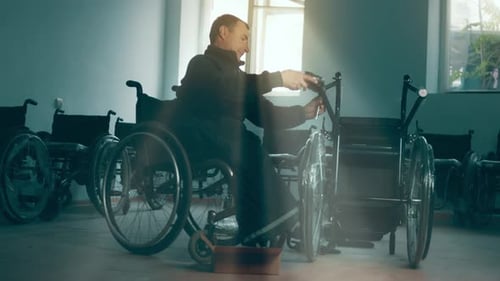 Man in Wheelchair Adjusting Another Wheelchair Indoors