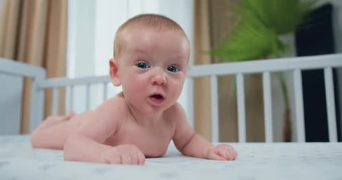 Happy Infant Lying in a White Crib