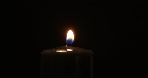 lights black paraffin candle using a match on a dark background. Bright flame, fire, ignition.