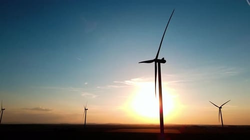 Silhouetted Wind Turbines in Countryside Landscape During Sunset