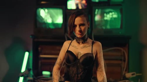 Tattooed Woman Poses in Darkly Lit Room