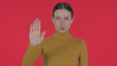 Porträt einer stoppenden lässigen jungen Frau auf rotem Hintergrund