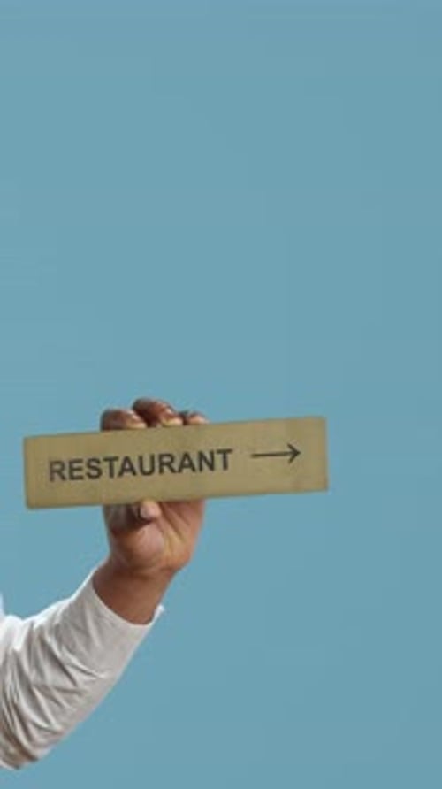 Vertical Video Doorman Bellhop Showing the Restaurant Direction with a Hotel Sign