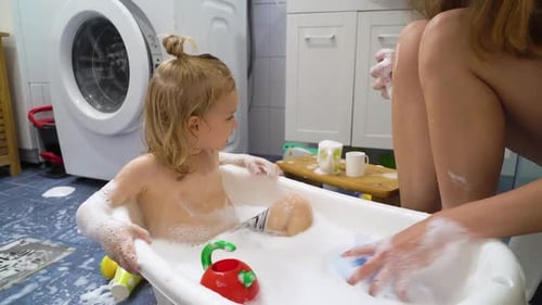 Mother Giving Child Bubble Bath with Toys