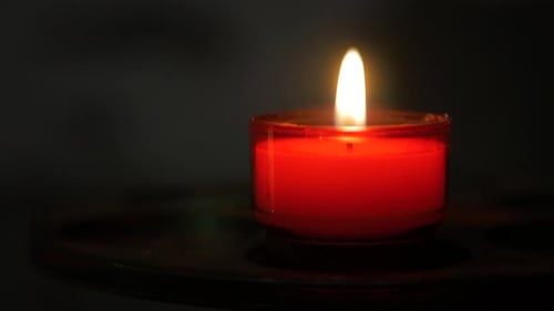 Burning red candle isolated on black background, resembles concepts of religion, romance love and fe