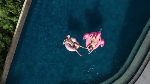 Young Adults Relaxing on Inflatable Floats in Pool