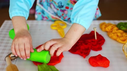 Child Playing with Bright Modeling Clay at Table