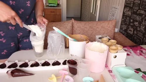 A Woman Puts Ice Cream Mixture Into A Pastry Bag. Nearby Is A Silicone Mold Smeared With Chocolate